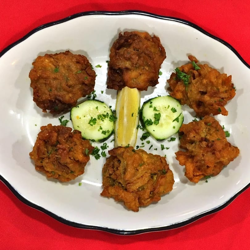 Halal King Indian Grill's pakoras, garnished with parsley, cucumber slices, and a lemon wedge.