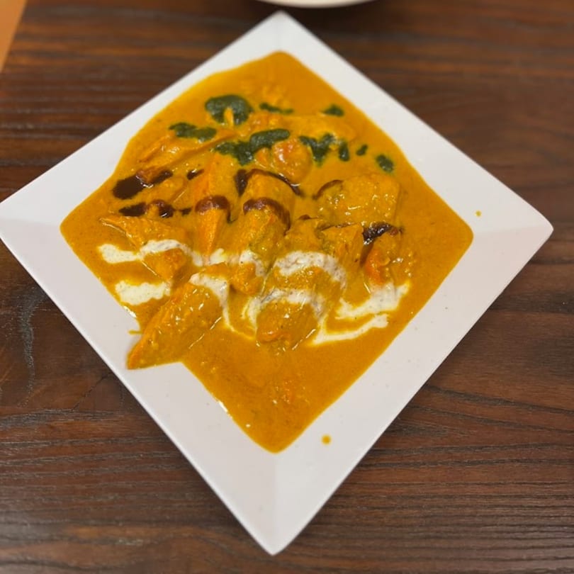 Indian chicken tikka masala with creamy sauce, green herb oil, and dark balsamic glaze.
